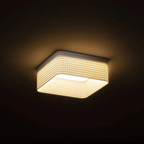Neliömallinen LED-valaisin syttyneenä, antaa pehmeää ja lämpimän sävyistä valoa.