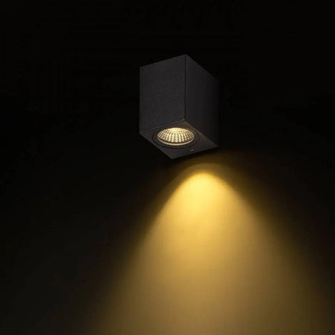 LED-seinävalaisin käytössä, heijastamassa yksisuuntaista lämmintä valoa alaspäin ulkoseinällä.